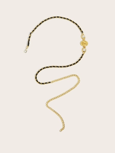 Detail of gold chain belt featuring black leather weave, pearls, and vintage coin pendant