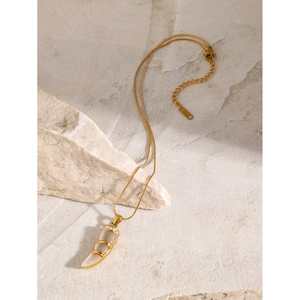Macro detail of 18k gold plated crescent pendant with cat eye stone on stone surface