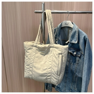 Detail of beige quilted tote bag showing padded nylon fabric and premium stitching texture