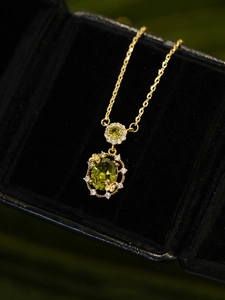 Macro view of vintage 18K gold plated oval green zircon pendant with butterfly detail