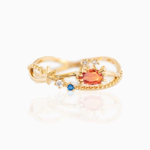Ocean-inspired gold ring with orange oval gemstone and blue zircon star accents