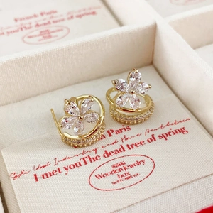 Detail showing high-quality cubic zirconia flower studs with gold finish on a white jewelry box