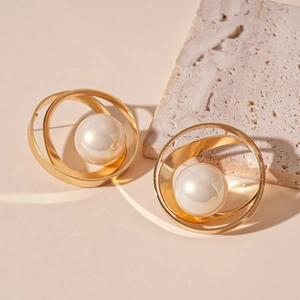 Gros plan détaillé de boucles d'oreilles géométriques dorées avec une perle blanche centrale