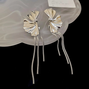 Detailed view of silver flower earrings with long fringe tassels on textured prop