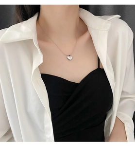 Close-up of heart-shaped pendant necklace with polished mirror finish on model