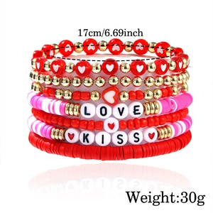 Detail showing stacked boho beaded bracelets with LOVE and KISS letters and heart charms
