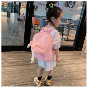 Rear view of a girl wearing a pink plush flamingo backpack with 3D wings in a cafe
