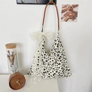 Détail d'un sac fourre-tout en toile florale avec nœud en dentelle et bandoulière