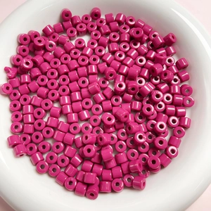 Dettaglio di perline cilindriche in acrilico rosa in una ciotola bianca per gioielli