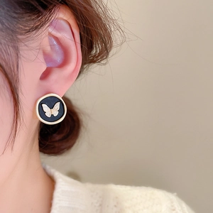 Close-up of vintage butterfly round stud earrings with golden relief on black disk