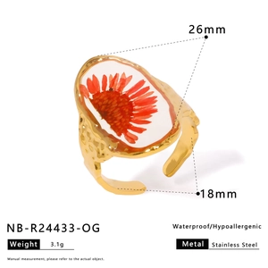 Macro view of gold stainless steel ring featuring red dried flower heart and size specs