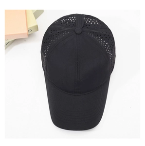 Detail view of black quick-dry baseball cap showing laser-cut holes for ventilation