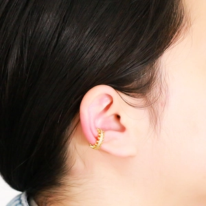 Detailed view of irregular gold ear cuff with white zircon stones on model's ear