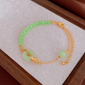 Détail du collier avec perles en jade synthétique, feuille de ginkgo dorée et pendentif chinois