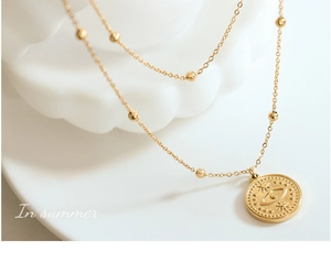 Detail of 18k gold double-layer necklace featuring evil eye pendant and beaded chain