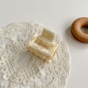 Detail view of marble pattern acetate claw clip on beige lace background