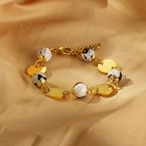 Close-up of golden polished discs and marble resin beads on a luxury satin background