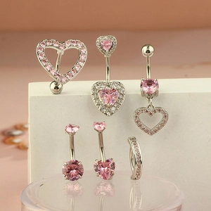 Set of pink zircon heart navel rings on a white stone pedestal with soft pink background
