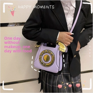 Detailed view of purple telephone-shaped crossbody bag with gold dial and slim strap