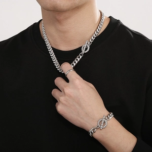 Gros plan sur la chaîne et le bracelet gourmette argentés avec fermoir strass brillant