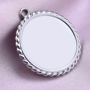Close-up of a silver round metal pendant tray with twisted rope edge on purple fabric