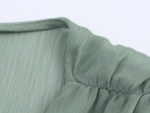 Detaillierte Nahaufnahme der Plissee-Textur und feinen Nähte am Chiffonkleid-Ausschnitt
