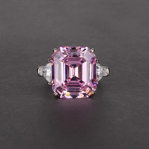 Close-up of emerald cut pink gemstone ring with triangular white side stones in silver