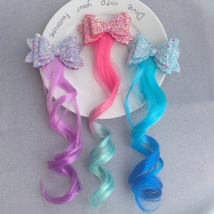 Close-up of glitter bow hair clips with colorful gradient synthetic hair extensions