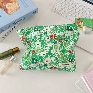 Macro detail of the green floral makeup bag featuring a fabric brand label on its surface