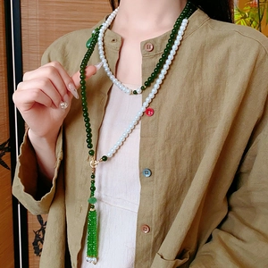 Détail du collier de perles avec pompon vert porté par un mannequin sur fond vintage