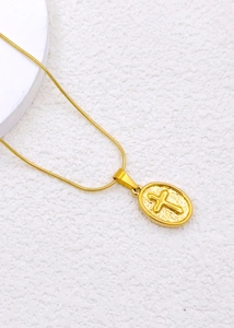 Detailed close-up of golden oval cross pendant necklace with a sleek snake chain