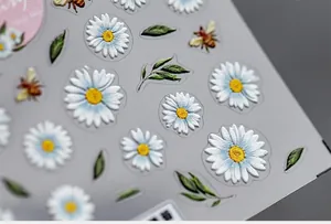 Macro shot of 3D embossed daisy and honeybee nail stickers with a minimalist floral design