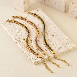 Bohemian gold plated bracelets with colorful zircon stones on light textured stone background