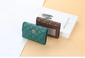 Detail of green and brown quilted leather card holders with gold hexagonal metal buckles