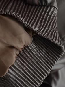 Detail of dark brown faux leather jacket showing fine texture and ribbed cuff craftsmanship
