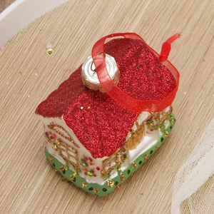 DIY Christmas house ornament with red roof and glitter finish on a wooden background
