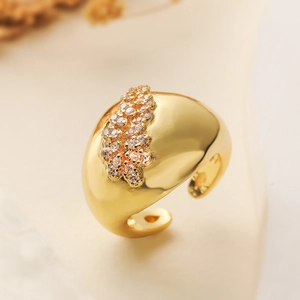 Luxurious wide gold geometric hoop earring with sparkling zircon insets on a beige background