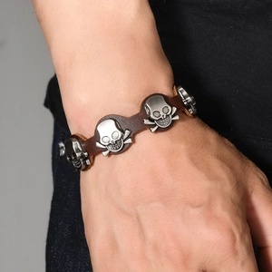 Vintage men's brown leather bracelet with silver skull charms on a professional male model