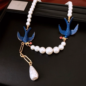 Detail of pearl necklace with blue enamel swallows and irregular pearl drop pendant