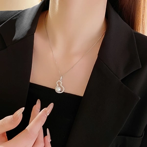 Detail of silver gourd pendant necklace with zircon and white pearl on model neck