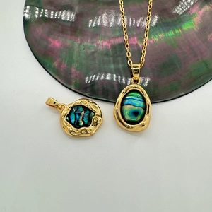 Detail view of 18K gold-plated oval pendants with natural abalone shell inlays