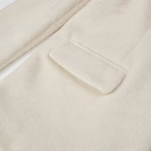 Detail shot of the cream white faux fur texture and pocket flap on the coat
