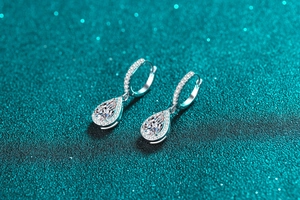 Macro shot of silver teardrop-shaped moissanite earrings with micro-pave diamond details
