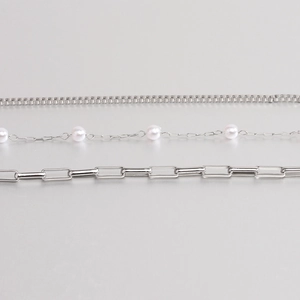 Detailed close-up of triple-layered silver chains featuring pearls and thick curb links