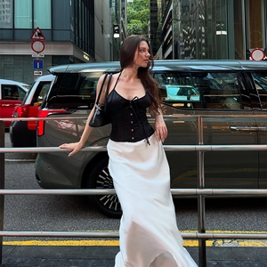 Detail of a black halter corset top paired with a flowing white satin midi skirt