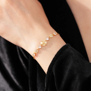 Detailed view of a gold flower bracelet with opal and zircon worn on a female wrist