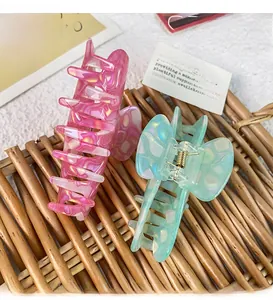 Detailed close-up of marble pattern acetate hair claw clips on a woven rattan mat