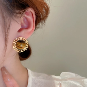 Retro round tiger eye earrings with golden lace borders on female model ear