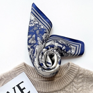 Artistic silk square scarf with landscape print on soft beige knitted sweater backdrop