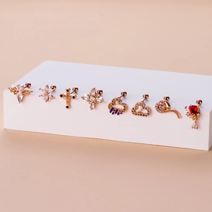 Macro view of eight rose gold surgical steel cartilage earrings with crystal accents